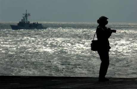 US Navy 021116-N-3236B-014 PH3 Lindsay Minturn, of Sequim, Wash., a photographer stationed aboard Kitty Hawk, photographs American and Japanese Maritime Self-Defense Force (JMSDF) ships from the flight deck of the ship