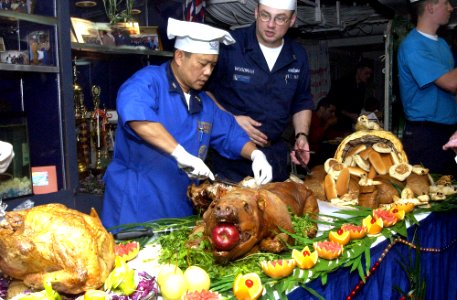 US Navy 021224-N-4142G-009 Master Chief Mess Management Specialist Arsenio Villanueva prepares cooked pig for Christmas dinner
