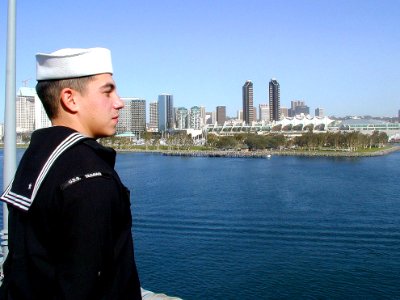 US Navy 030106-N-5666L-001 A crewmember looks on as the ship leaves her homeport of San Diego, Calif