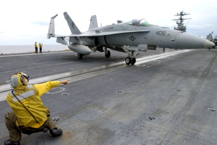 US Navy 021209-N-6895M-502 plane director guides an F-A-18 into position on the ship's flight deck