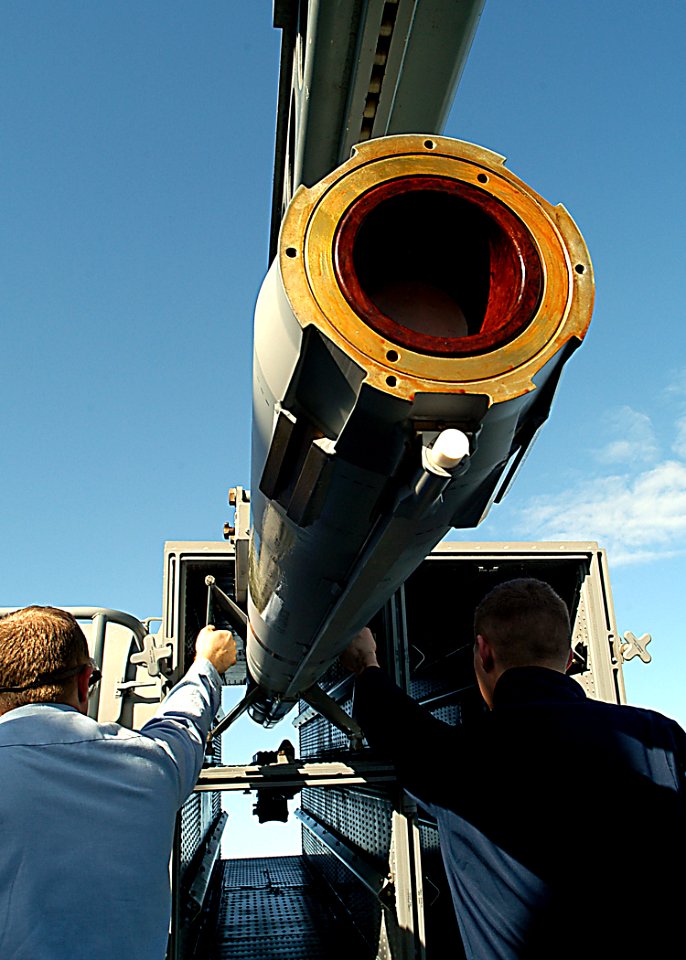US Navy 030205-N-4048T-069 Fire Controlmen hold the wing clips closed on a NATO RIM-7 Sea Sparrow missile while uploading it into a launcher cell