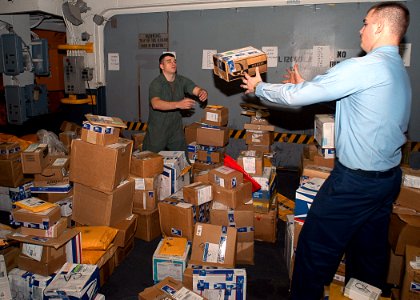 US Navy 030305-N-1512S-070 LCpl Adam Hadjis passes Postal Clerk 3rd Class Brian Etcheson a package while sorting in coming mail in the Lower Vehicle Stowage aboard the amphibious assault ship USS Kearsarge