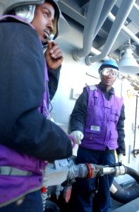 US Navy 030226-N-6141B-005 Engineman Fireman Calvin Lucas communicates to the ship's fuel console operator during a replenishment at sea operation