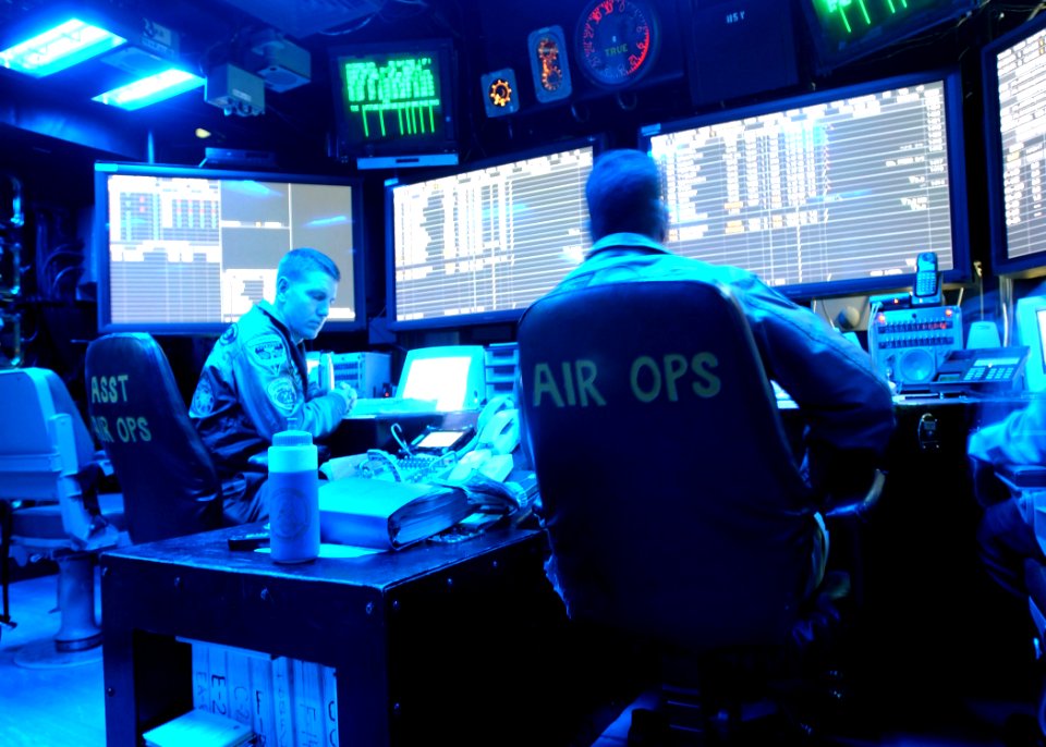 US Navy 021118-N-9593M-013 Commander Samuel Bovington, Air Operations Officer (seated left) and Lieutenant Commander Chris Banks Assistant Air Operations Officer (seated right), man watch stations in the ship's air operat
