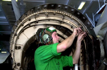 US Navy 030310-N-2143T-001 Aviation Structural Mechanic 3rd Class Jesse Weber works on the tail section of an F-A-18 Hornet in the ship's hanger bay photo