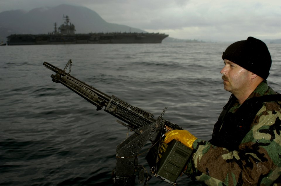 US Navy 030302-G-3024G-002 Electronic Technician 1st Class Warren Chinn assigned to Inshore Boat Unit Twenty Six (IBU 26) watches over USS Theodore Roosevelt (CVN 71)