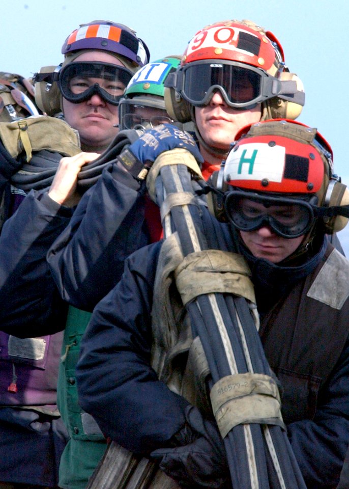 US Navy 030225-N-3235P-506 Flight deck personnel work together to re-stow the fixed wing aircraft arrested landing emergency barricade following a successful morning of flight deck training on Truman during a general quarters