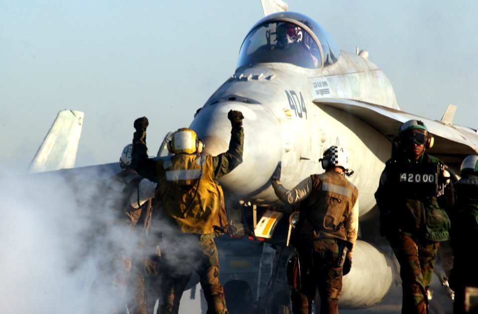 US Navy 030228-N-1810F-011 An aircraft director signals an F-A-18C strike fighter to stop in position for launch from one of four steam driven catapults on the flight deck aboard USS Kitty Hawk (CV 63)