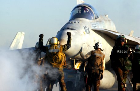 US Navy 030228-N-1810F-011 An aircraft director signals an F-A-18C strike fighter to stop in position for launch from one of four steam driven catapults on the flight deck aboard USS Kitty Hawk (CV 63)