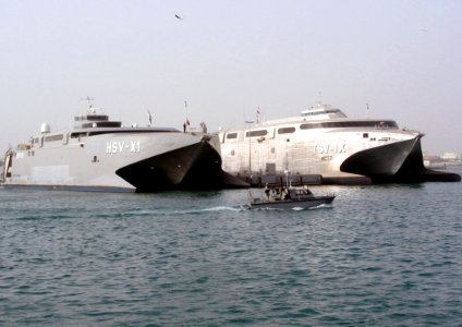 US Navy 030225-N-1050K-001 Sealift vehicles belonging to the U.S. Navy and U.S. Army sit together pier side under the watchful eye of both the U.S. and Kuwaiti harbor patrol