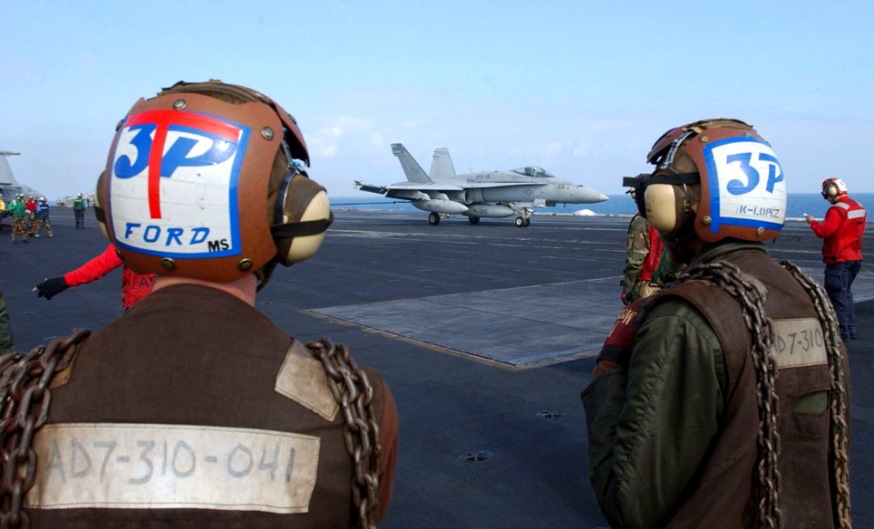 US Navy 030314-N-6895M-506 Two plane captains watch as an F-A-18 Hornet ands on the flight deck