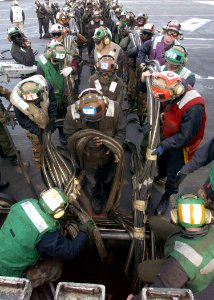 US Navy 030225-N-3235P-501 Flight deck personnel work together to re-stow the fixed wing aircraft arrested landing emergency barricade following a successful morning of flight deck training on Truman during a general quarters d
