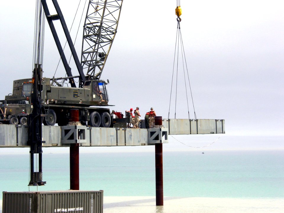 US Navy 030404-N-1050K-023 U.S. Navy Seabees assigned to Amphibious Construction Battalions One and Two prepare to place the next roadway section being used in the building of the Elevated Causeway System-Modular (ELCAS (M)) st