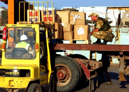 US Navy 030328-N-2513W-068 Humanitarian Assistance (HA) supplies are placed on a flatbed truck by a forklift delivery to the Iraqi people by Coalition forces at the port of Umm Qasr photo