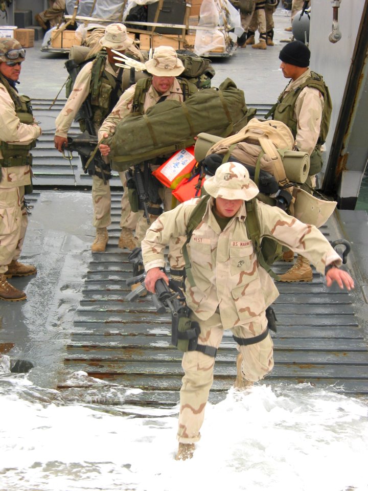 US Navy 030322-N-1050K-012 Marine Pfc. West jumps from a Landing Craft Utility vessel onto the dry land of Camp Patriot