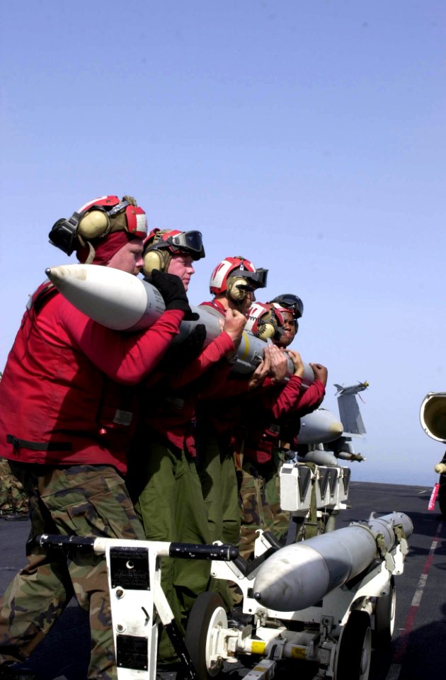 US Navy 030408-N-2385R-004 Aviation Ordnancemen lift an Advanced, Medium-Range, Air-to-Air Missile (AMRAAM) to attach it onto an F-A-18 Hornet aboard USS Nimitz (CVN 68)