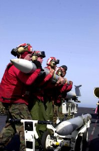 US Navy 030408-N-2385R-004 Aviation Ordnancemen lift an Advanced, Medium-Range, Air-to-Air Missile (AMRAAM) to attach it onto an F-A-18 Hornet aboard USS Nimitz (CVN 68)