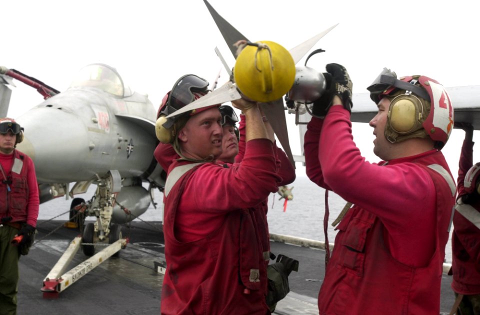 US Navy 030412-N-2385R-010 Aviation Ordnancemen lift an AIM-9M Sidewinder air-to-air missile to upload it onto an F-A-18 Hornet aboard USS Nimitz (CVN 68)