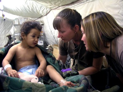 US Navy 030410-N-0728B-001 Hospital Corpsman 1st Class Jody Stenquist from Pontiac, Mich., and Hospital Corpsman 2nd Class Sara Beishir from St. Louis, Mo help a young patient photo