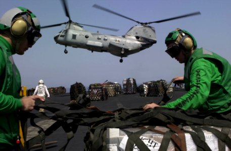US Navy 030415-N-8273J-001 Crewmembers aboard USS Nimitz (CVN 68) unload nearly 300 pallets of supplies on the flight deck during a Vertical Replenishment (VERTREP) with the fast combat support ship USS Bridge (AOE 10)