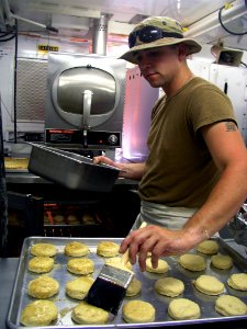 US Navy 030418-N-0728B-002 Mess Specialist 2nd Class Charles Mansfield assigned to Naval Hospital Pensacola on detachment to Fleet Hospital Three (FH-3), puts the finishing touch on a batch of biscuits before placing them in th