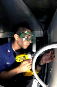 US Navy 030401-N-1577S-002 Hull Technician 2nd Class David Chapa from Pleasanton, Texas, lines up his drill to begin installation of an electrical outlet aboard USS Nimitz (CVN 68) photo
