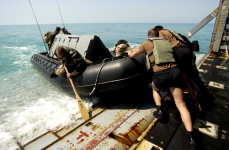 US Navy 030317-N-5319A-011 Members of the Deep-Shallow Water Mark 7 crew from Commander Task Unit (CTU-55.4.3) push their dive boat off the well deck of the USS Gunston Hall (LSD 44)