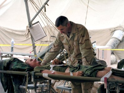 US Navy 030408-N-0728B-002 U.S. Navy Chaplain, Lt. Cmdr. John Denton visits with U.S. Marine Corps. Cpl. Marco Chavez while in the casualty receiving area of Fleet Hospital Three photo