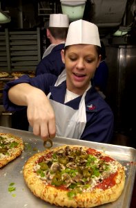 US Navy 030419-N-1577S-001 Information Systems Technician 1st Class Shannea Vorous prepares pizza for the crew of USS Nimitz (CVN 68) and Carrier Air Wing 11 (CVW-11) as part of the First Class Pizza Night