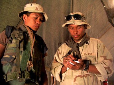 US Navy 030401-N-0728B-001 Hospital Corpsman 1st Class Roseller Flores (right) writes a letter for twin brother Hospital Corpsman 1st Class Alexis Flores to deliver to his wife upon his return to Camp Pendleton