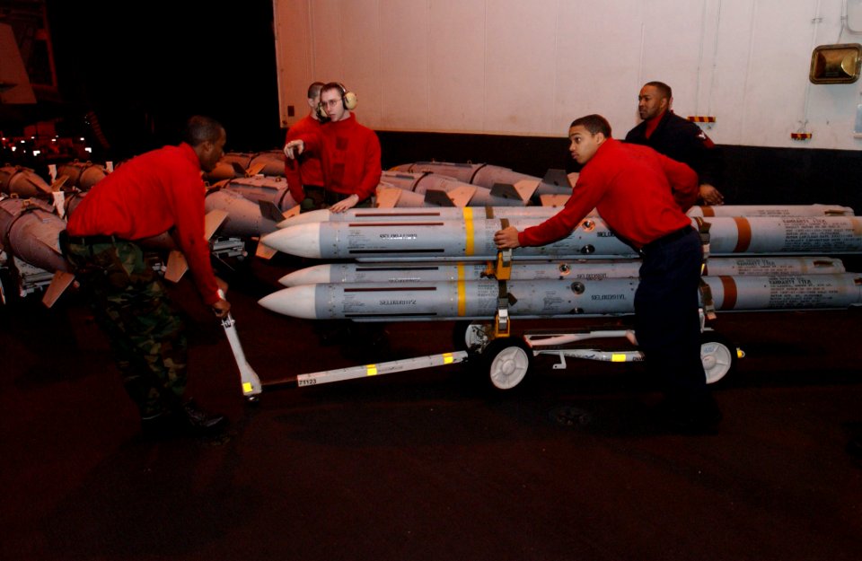 US Navy 030323-N-1328C-506 Aviation Ordnancemen assigned to weapons department, transfer radar-guided AIM-7 Sparrow air-to-air missiles across the ship's hangar bay