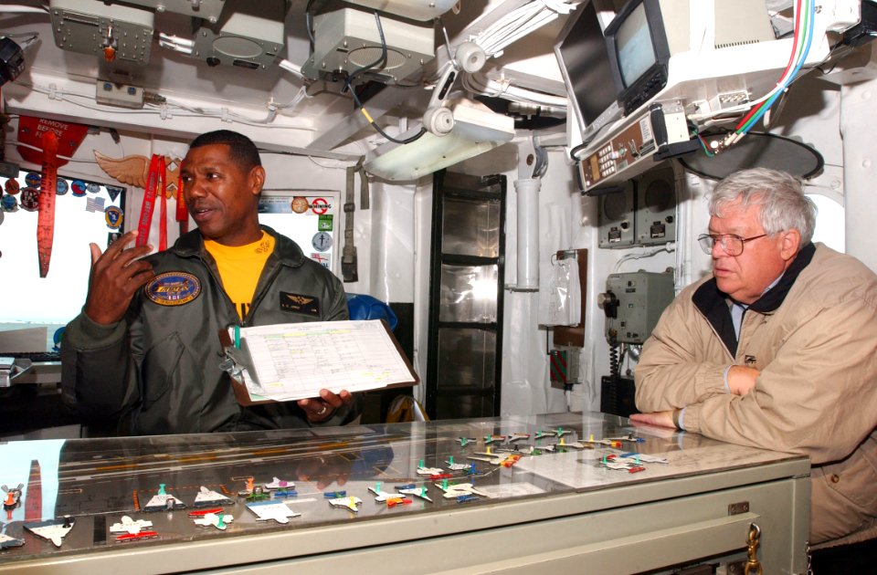 US Navy 030423-N-7781D-003 Lt. Cmdr. Richard Jones, explains his position as Handling Officer to the Speaker of the House, J. Dennis Hastert, and other congressional visitors in the ship's flight deck control aboard USS