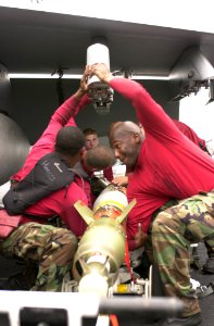 US Navy 030413-N-1577S-003 Aviation Ordnancemen load laser guided munitions onto an F-A-18E Super Hornet on the flight deck aboard USS Nimitz (CVN 68) photo