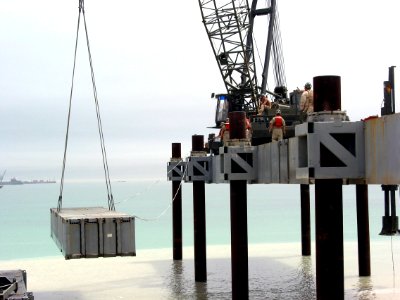 US Navy 030404-N-1050K-020 U.S. Navy Seabees assigned to Amphibious Construction Battalions (ACB) One and Two lift the next roadway section to be used in the building of the Elevated Causeway System-Modular (ELCAS (M)) structur