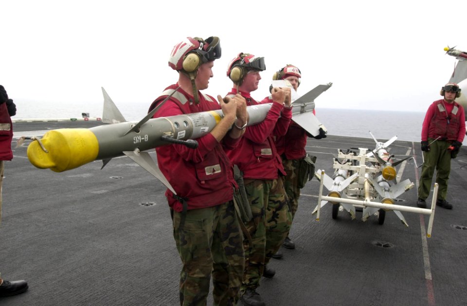 US Navy 030412-N-2385R-011 Aviation Ordnancemen lift an AIM-9M Sidewinder air-to-air missile to upload it onto an F-A-18 Hornet aboard USS Nimitz (CVN 68)