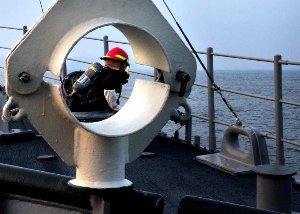 US Navy 080819-N-0807W-298 A Sailor ascends from a hatch wearing a self-contained breathing apparatus after conducting a fire drill