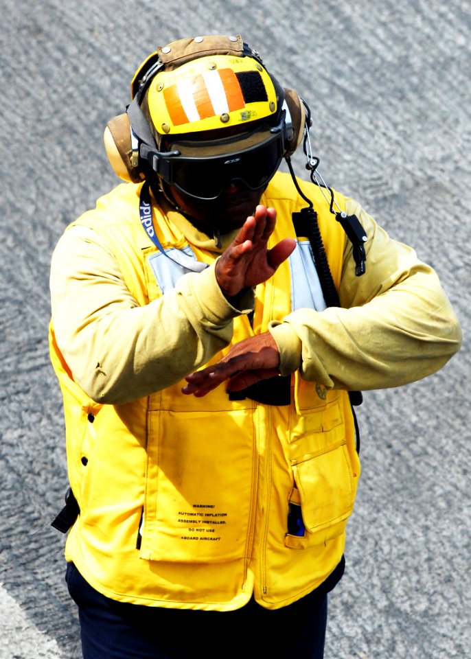 US Navy 080922-N-2183K-107 A flight deck crewman uses hand signals to communicate with other personnel on the flight deck