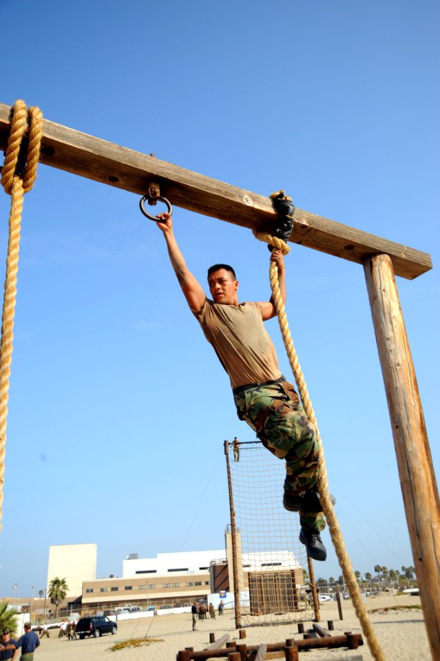 US Navy 080715-N-2959L-349 Seaman Apprentice Eduardo Martinez concentrates on maneuvering to the next rope during and obstacle course