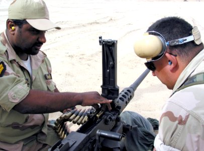 US Navy 030412-N-1050K-033 Pvt. Mubarek, a Kuwaiti Sailor assigned to a Force Protection Team loads a strand of ammunition into a M2 .50 caliber machine gun under the watchful eye of Gunner's Mate 2nd Class Miguel Martinez