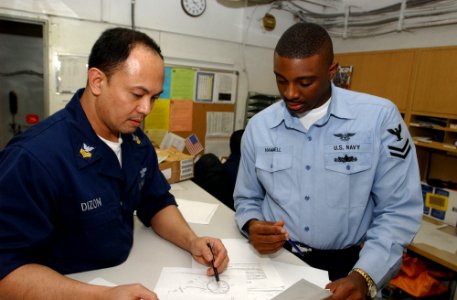 US Navy 030415-N-4953E-004 Aviation Storekeeper 2nd Class Gregory Hammel performs customer service duties verifying needed part numbers with a customer in the ships supply department aboard USS Harry S. Truman (CVN 75)
