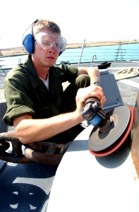 US Navy 030426-N-6141B-009 Seaman Nicholas Dalton from Corpus Christi, Texas, polishes one of the ship's capstans