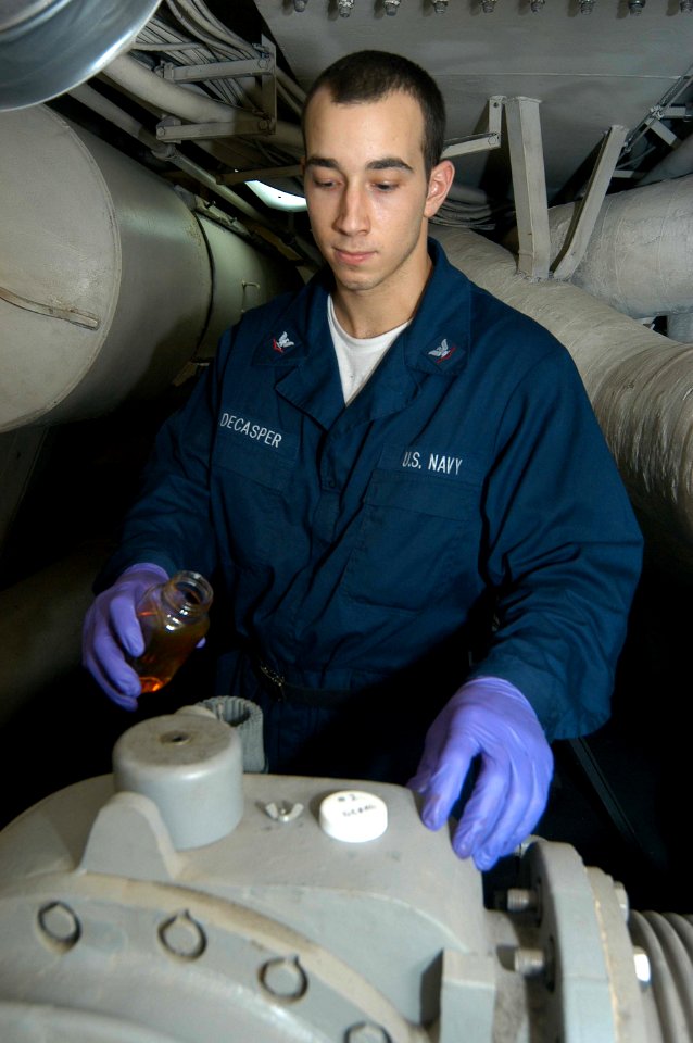 US Navy 030520-N-1512S-001 Machinist's Mate 3rd Class John Decasper pours hydraulic fluid into a diesel engine