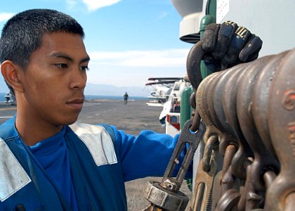 US Navy 030604-N-1512S-028 Airman Charles Imanil from Dededo, Guam, places a chain on the chock and chain holder on the flight deck aboard USS Kearsarge (LHD 3)