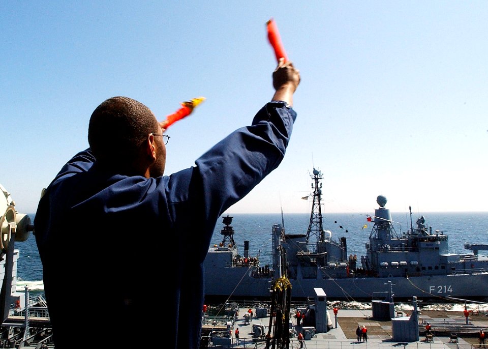 US Navy 030608-N-4374S-011 Signalman 3rd Class Cullen Braxton communicates with the German oiler FGS Rhoen (A 1443), using signal flags while receiving fuel