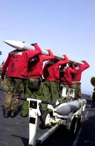US Navy 030408-N-2385R-005 Aviation Ordnancemen lift an Advanced, Medium-Range, Air-to-Air Missile (AMRAAM) to attach it onto an F-A-18 Hornet aboard USS Nimitz (CVN 68)