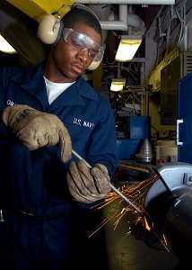 US Navy 030515-N-1512S-028 Fireman Apprentice Aaron Graham grinds down a rod in the ship's Electrical Motor Rewind Shop