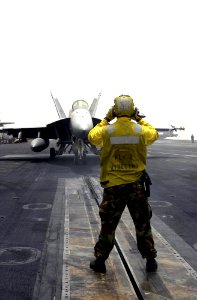US Navy 030517-N-9319H-006 Aviation Boatswain's Mate 1st Class Patrick Reynolds, from Queen Creek, Ariz., directs an F-A-18E Super Hornet assigned to the Tophatters of Strike Fighter Squadron Fourteen (VFA-14) into positi