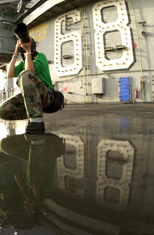 US Navy 030521-N-8273J-009 Photographer's Mate 3rd Class Yesenia Rosas photographs a flight deck cleaning exercise (SCRUBEX) on the flight deck aboard USS Nimitz (CVN 68)