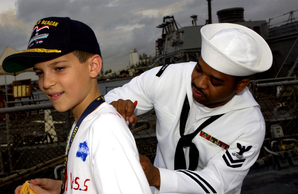 US Navy 030501-N-8787A-002 Postal Clerk 2nd Class Jamal Allison, assigned to the guided missile destroyer USS Cole (DDG 67) autographs a student's shirt during Fleet Week USA