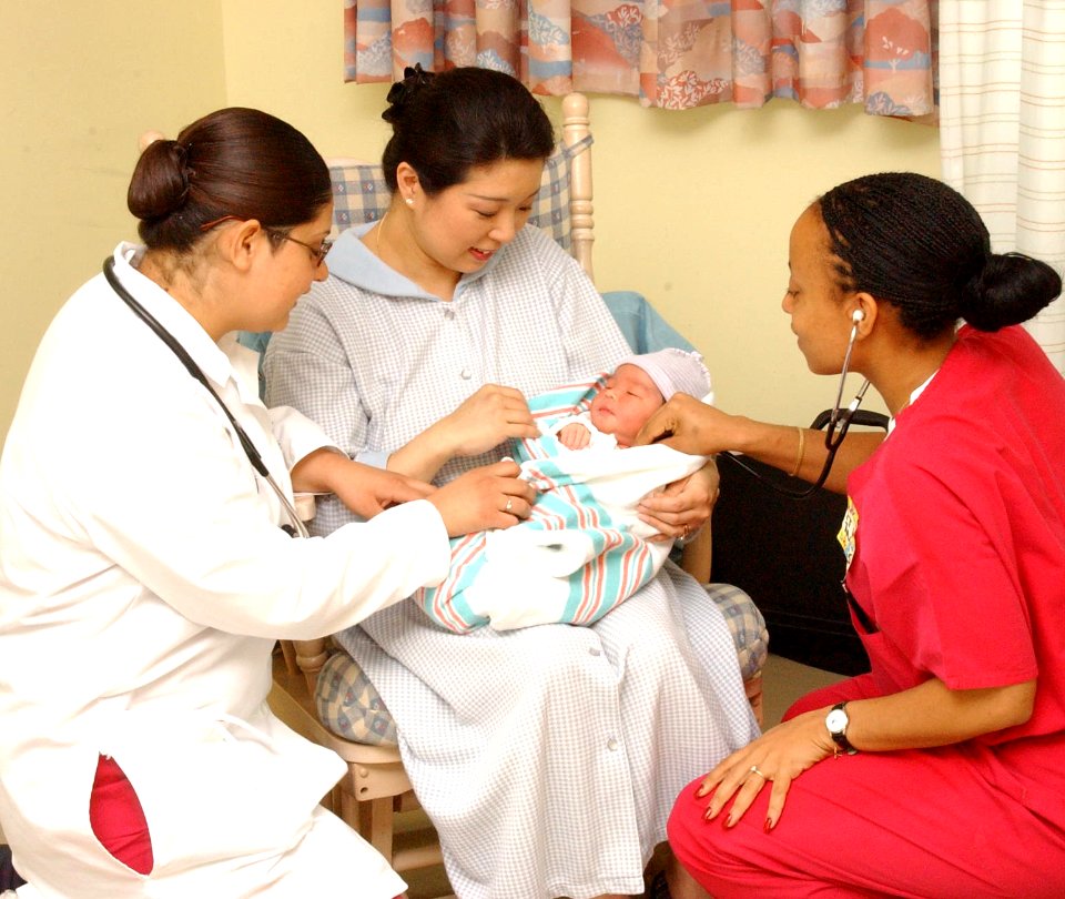 US Navy 030512-N-0000W-001 Hospital Corpsman Adoracion Samano and Navy Nurse Corps Officer Lt. Rhonda Hinds assist Lt.Cmdr. Kenneth R. Spurlock's wife on the Maternal Newborn Ward of U.S. Naval Hospital, Yokosuka, Japan